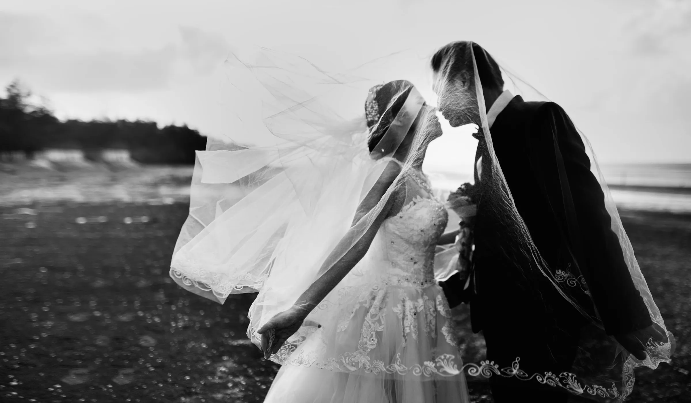 The couple kissing, the veil lifted by the wind, black and white
