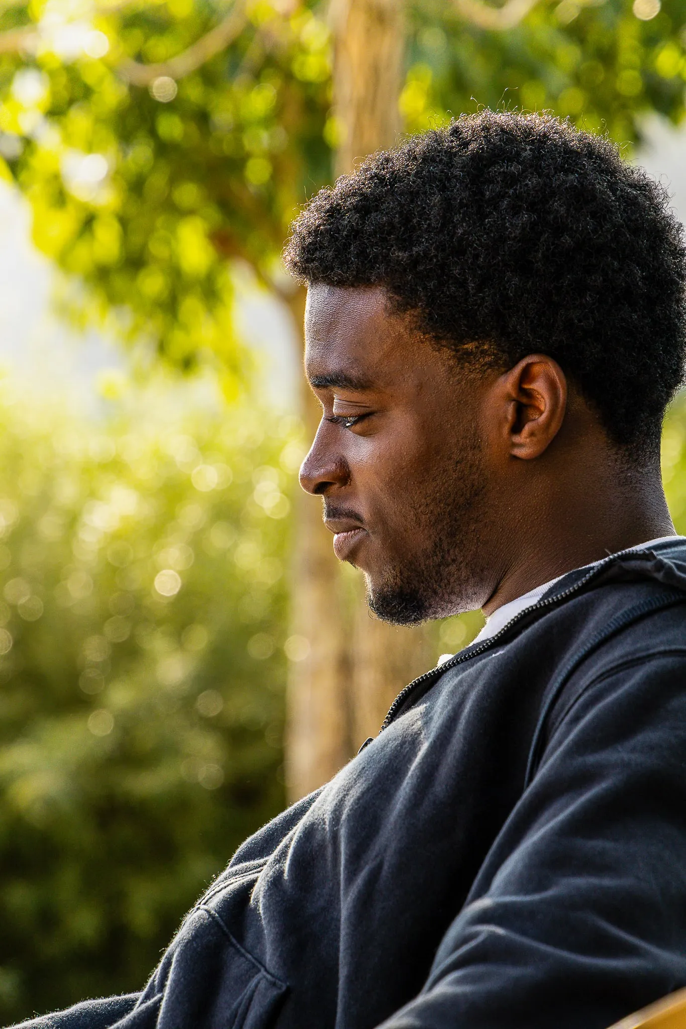Young man in profile, eyes lowered, golden light