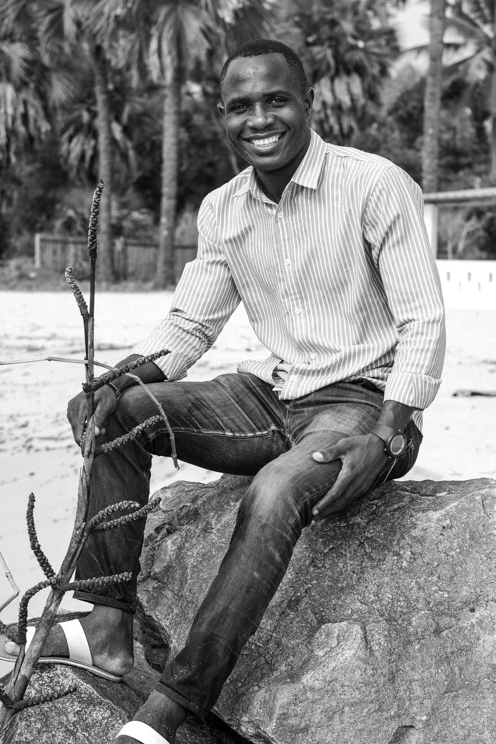 Smiling man sitting on a rock, in black and white